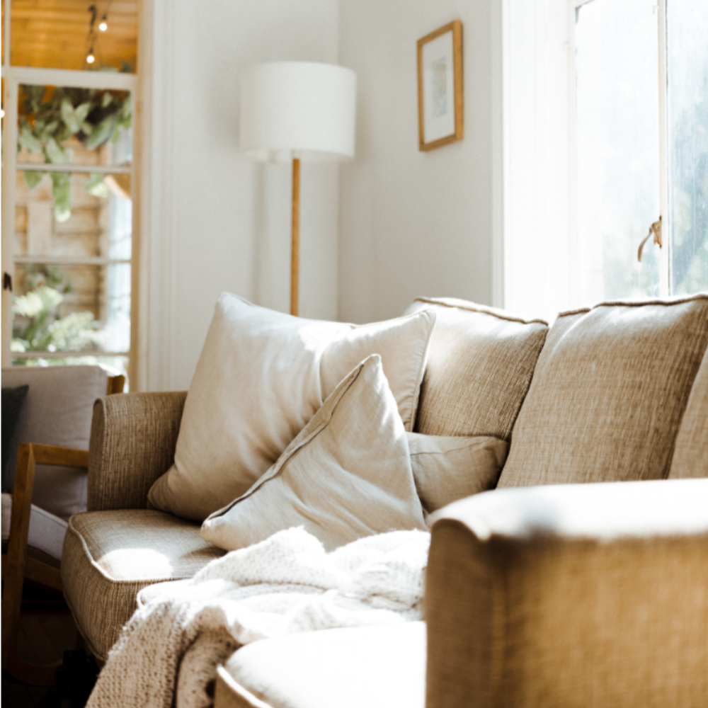 明るい日差しが差し込むリビングと柔らかなクッションのあるソファ